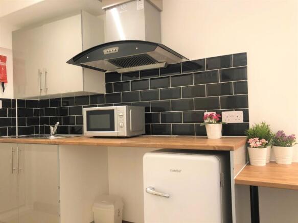 A modern kitchen featuring sleek black tiled ba...