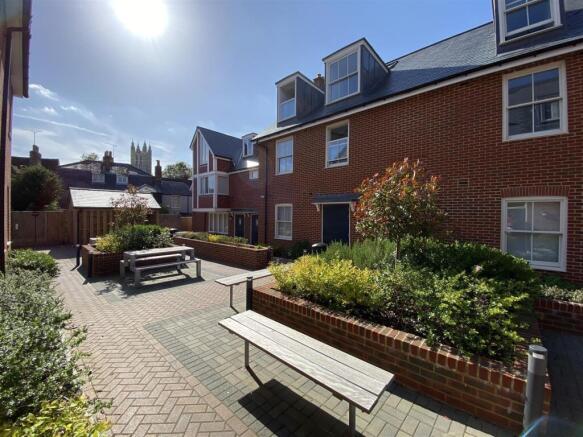 Sunny communal courtyard with seating and plant...