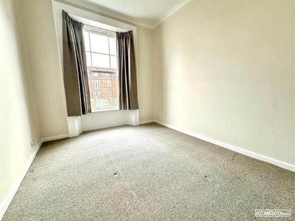 Bright bedroom with a large sash window and neu...