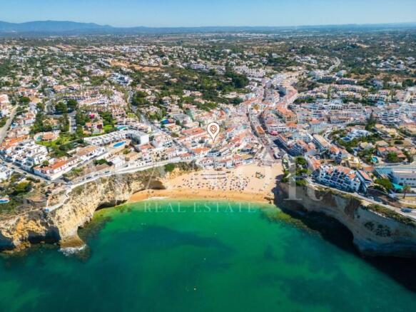 Aerial drone view of Carvoeiro beach in Algarve with turquoise water and cliffs near the property.
