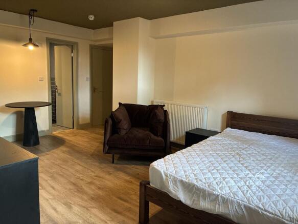 Spacious bedroom with stylish wooden flooring a...