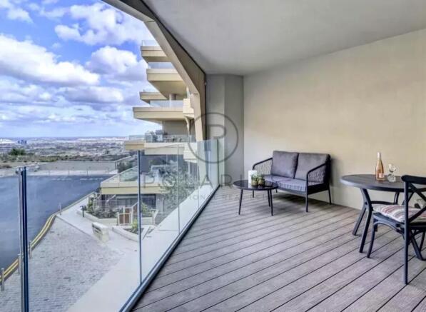 A modern balcony with glass railings features a sm