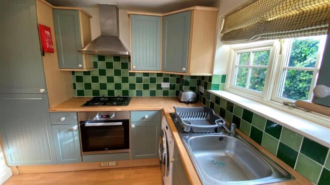 Modern kitchen with bright green tiling and win...