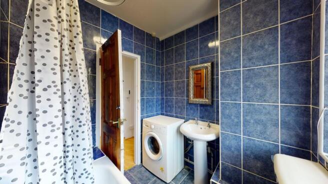 Bright bathroom with blue tiles and laundry are...