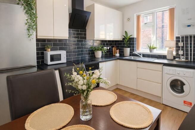 Modern fitted kitchen with dining table and pla...