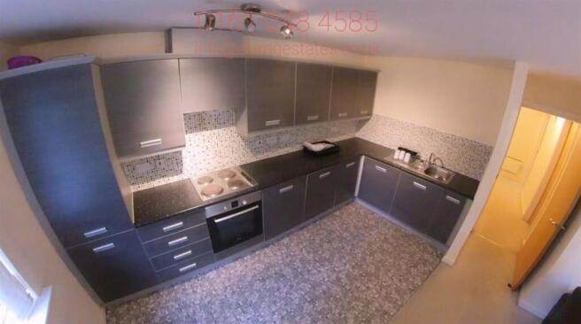 Modern galley-style kitchen with dark fitted ca...