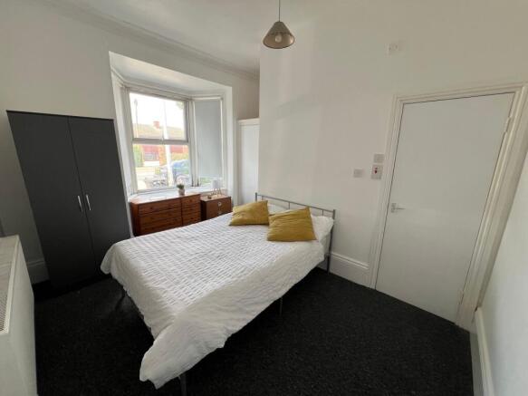 A bright double bedroom featuring a comfortable...