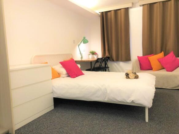 A cozy single bedroom featuring a comfortable b...