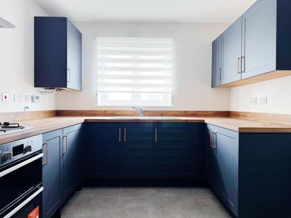 Bright, modern kitchen with deep navy shaker ca...