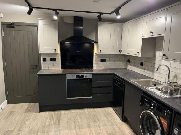 Contemporary fitted kitchen with matte black lo...