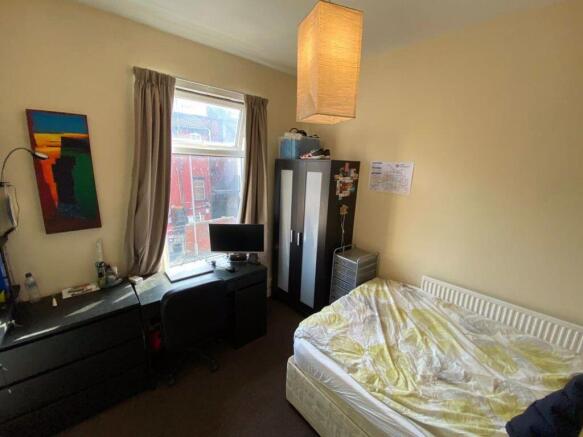 A cozy bedroom featuring a single bed with neat...