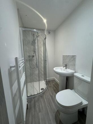 A modern bathroom featuring a curved glass show...