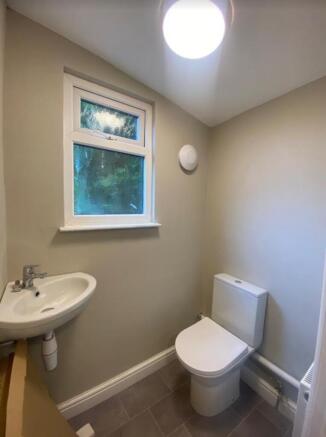 A clean and well-lit single toilet with a sink ...