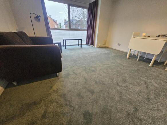 Bright living area with wall-to-wall carpet, a ...