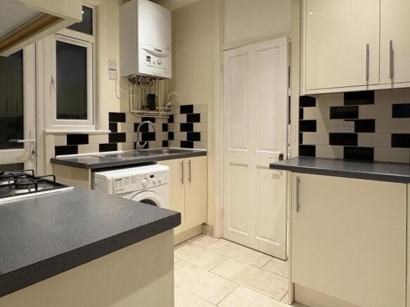 Neat modern kitchen with light cream cabinets, ...