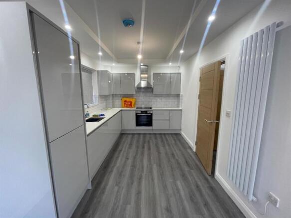 A modern, well-lit kitchen with sleek white cab...