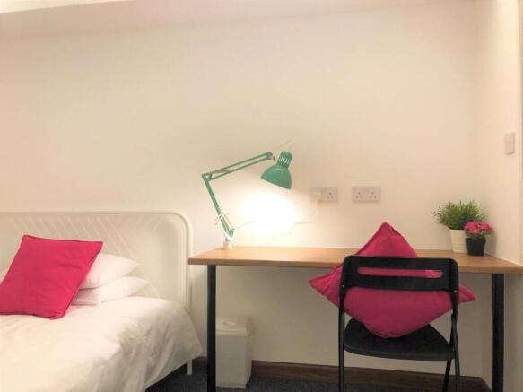 A tidy and cozy single bedroom featuring a whit...