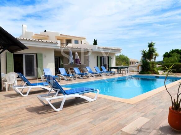 Luxury 4-bedroom villa for sale in Carvoeiro, Algarve, featuring a private swimming pool, sun loungers, and patio. Perfect holiday rental property investment near the beach.