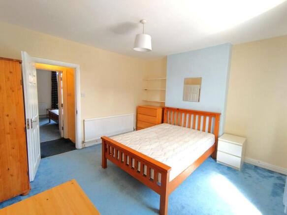 Bright double bedroom with a wooden bedframe, m...