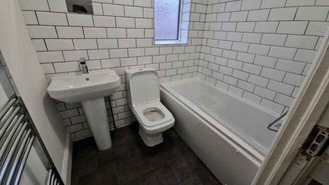 Modern tiled bathroom with bath and towel rail...