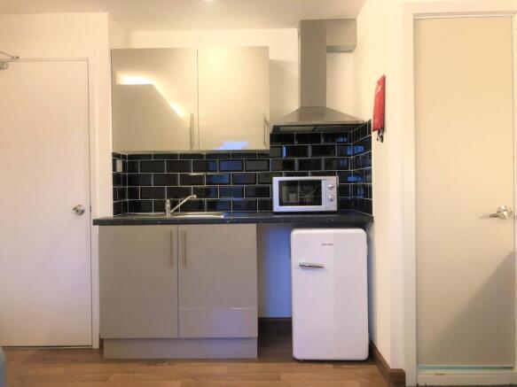 A modern compact kitchen featuring sleek grey c...