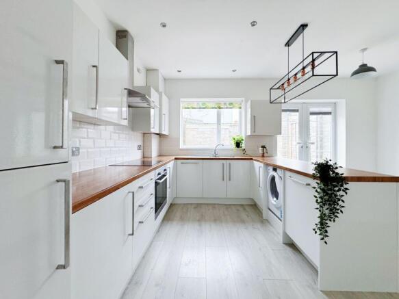 Bright, modern galley kitchen with white cabine...