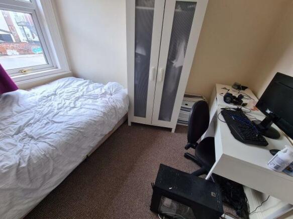 A neat and well-lit student bedroom featuring a...