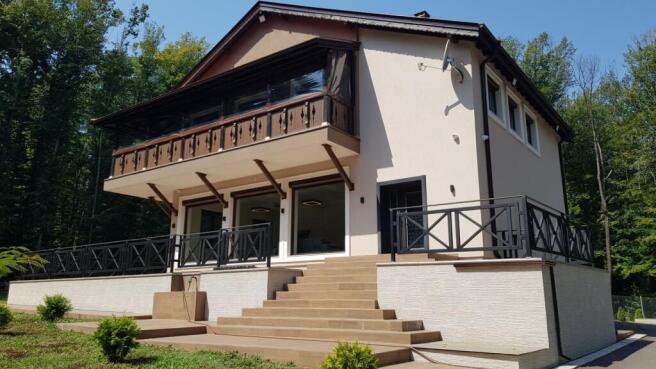 Side perspective showing balcony with wooden railing and stairs leading to terrace