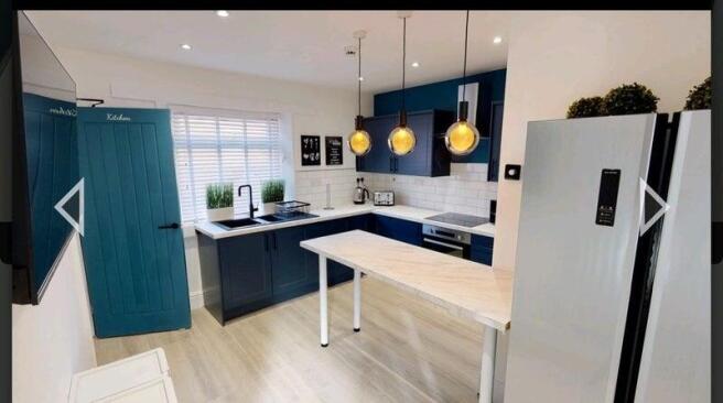 Bright modern kitchen with navy blue cabinetry,...