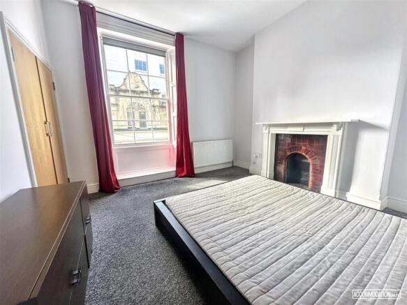 Spacious bedroom with large window and fireplac...