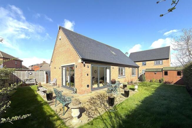 Sun-drenched garden with patio and lush lawn...