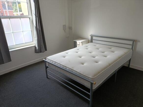 A bright double bedroom featuring a comfortable...