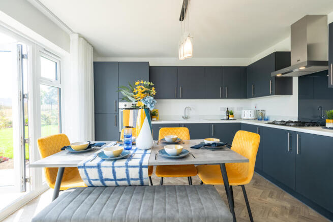 A modern kitchen with dark cabinets, a dining table with yellow chairs