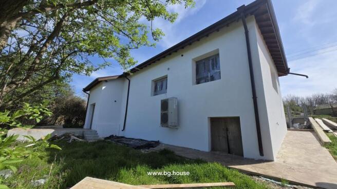 View of the white renovated house exterior showing new windows and an air conditioning unit mounted on the wall