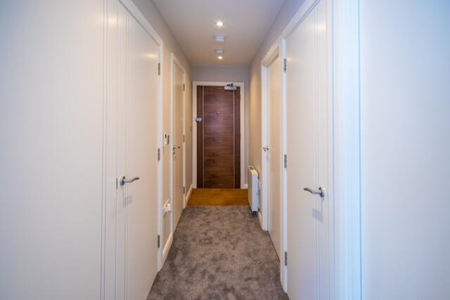 Bright, well-maintained hallway with soft carpe...