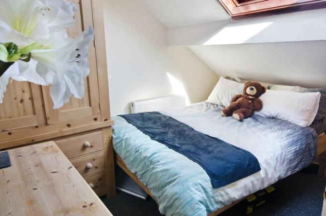 Bright, cozy attic bedroom with a comfortable d...