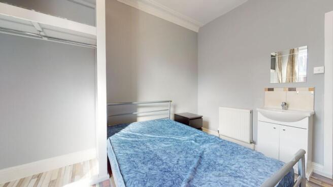 A cozy single bedroom featuring a bed with blue...