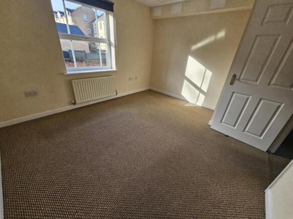 Bright, neutrally decorated bedroom with a larg...