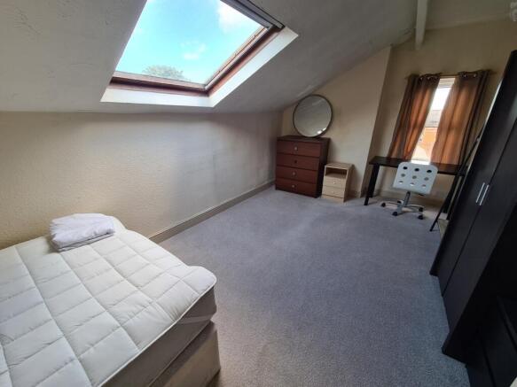 Bright and clean attic bedroom featuring a skyl...
