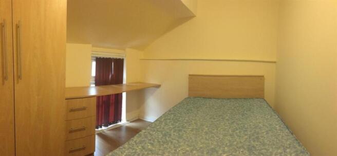 Cozy single bedroom with a built-in desk and sh...