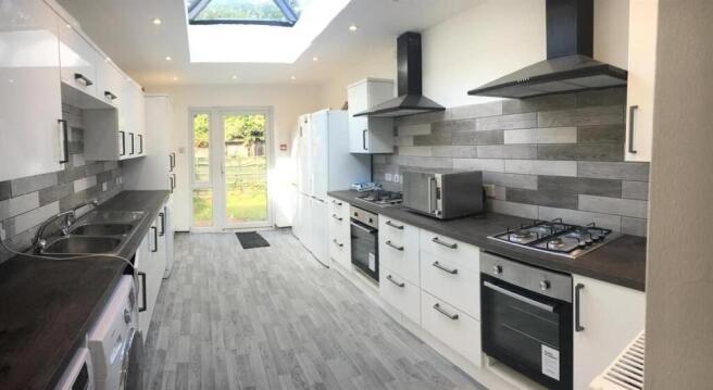 Long galley-style kitchen with modern white cab...