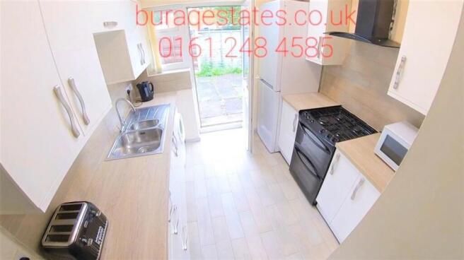 Bright modern galley kitchen with light wood co...