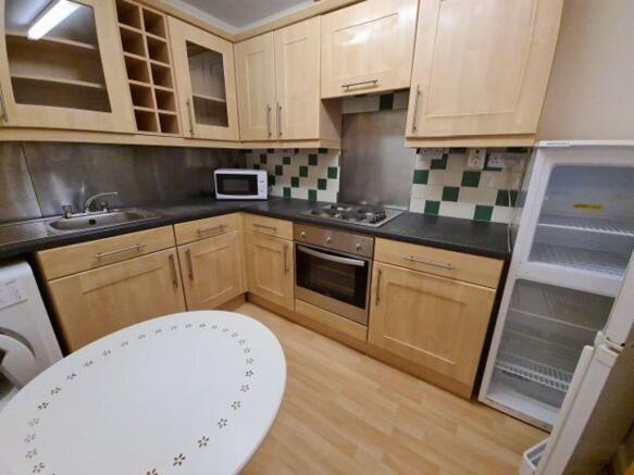 Well-equipped fitted kitchen with light wooden ...