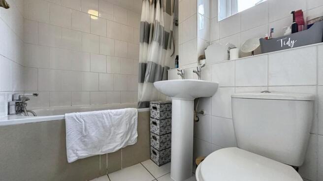 A clean and bright bathroom featuring a bathtub...