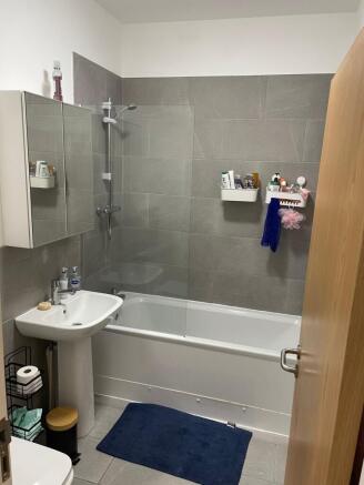 Modern tiled bathroom with a combined bath and ...