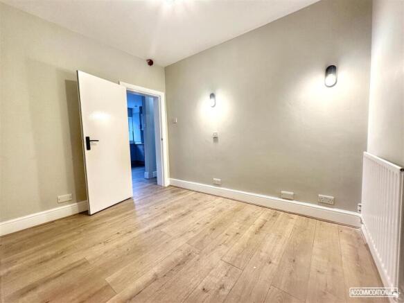 Bright, neutral bedroom with wood flooring...
