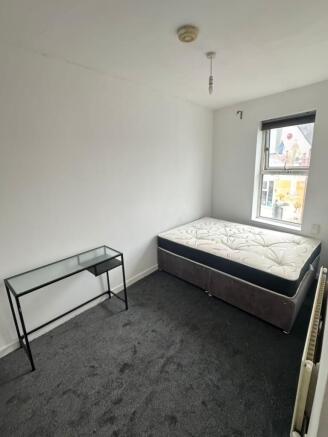 Bright, simply furnished bedroom with a double ...