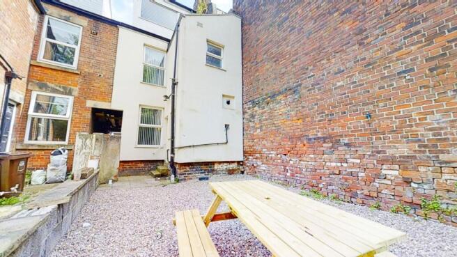Walled courtyard with a picnic bench on gravel,...