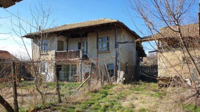 Exterior view of a traditional two-storey Bulgarian house with wooden balcony and tiled roof