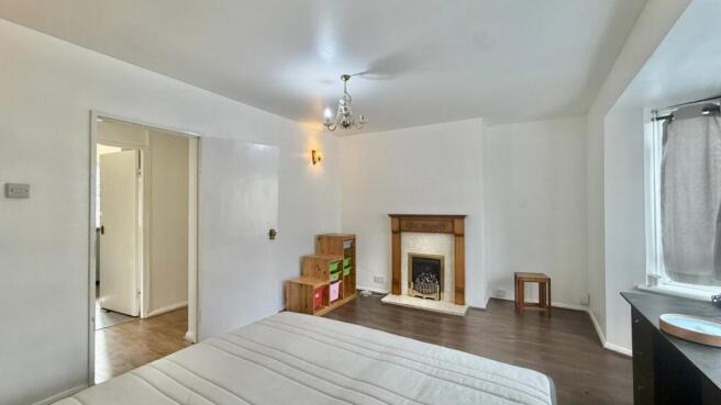 Spacious bedroom with fireplace and wooden floo...
